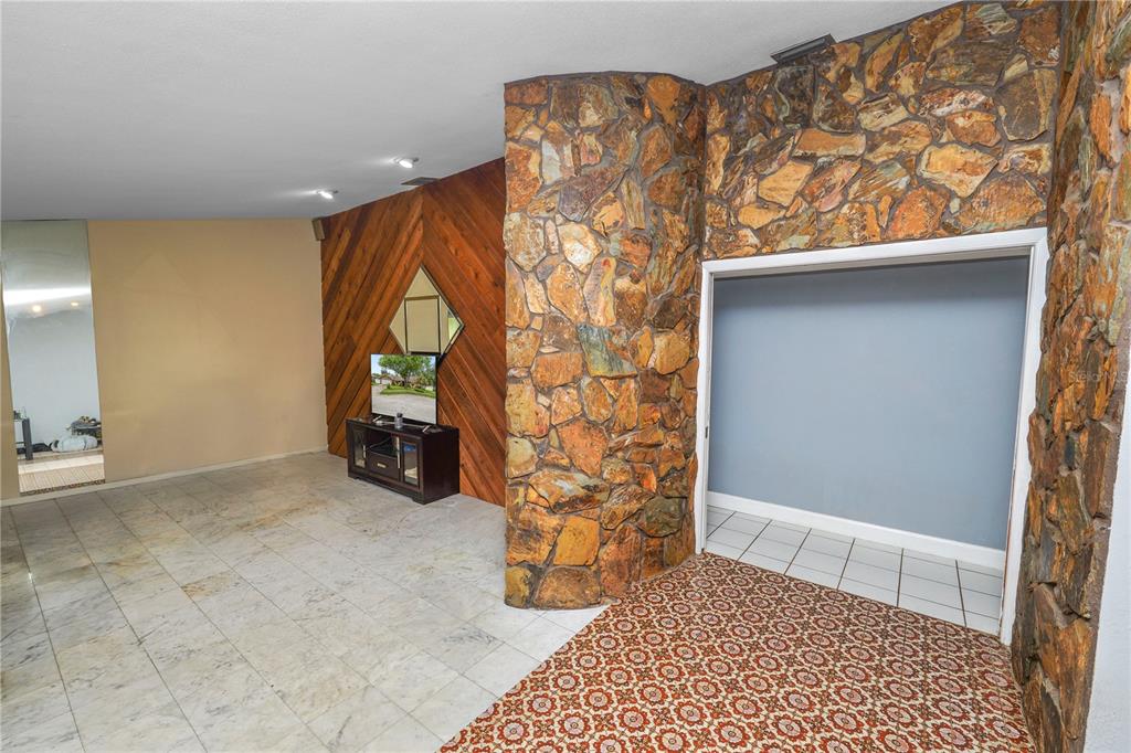 A room features a stone accent wall, wood paneling, and a mix of tiled flooring — 2010 MOSS COURT, DUNEDIN, FL