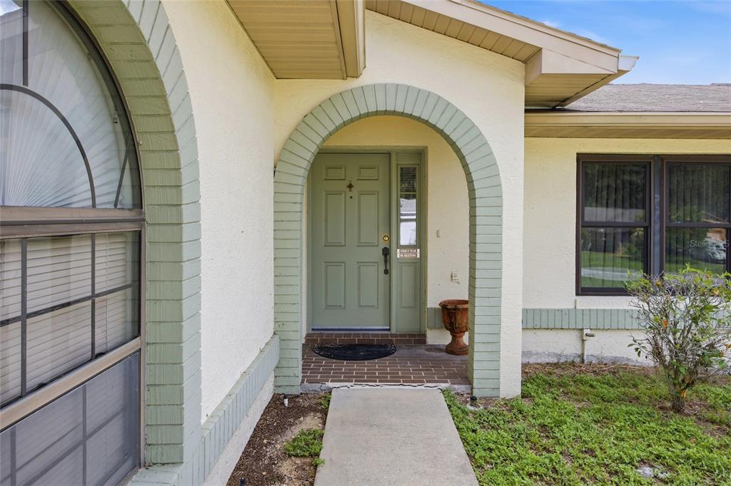 A front entrance features a green arched doorway, a brick porch, and a concrete walkway — 712 MAGNOLIA AVENUE, INVERNESS, FL