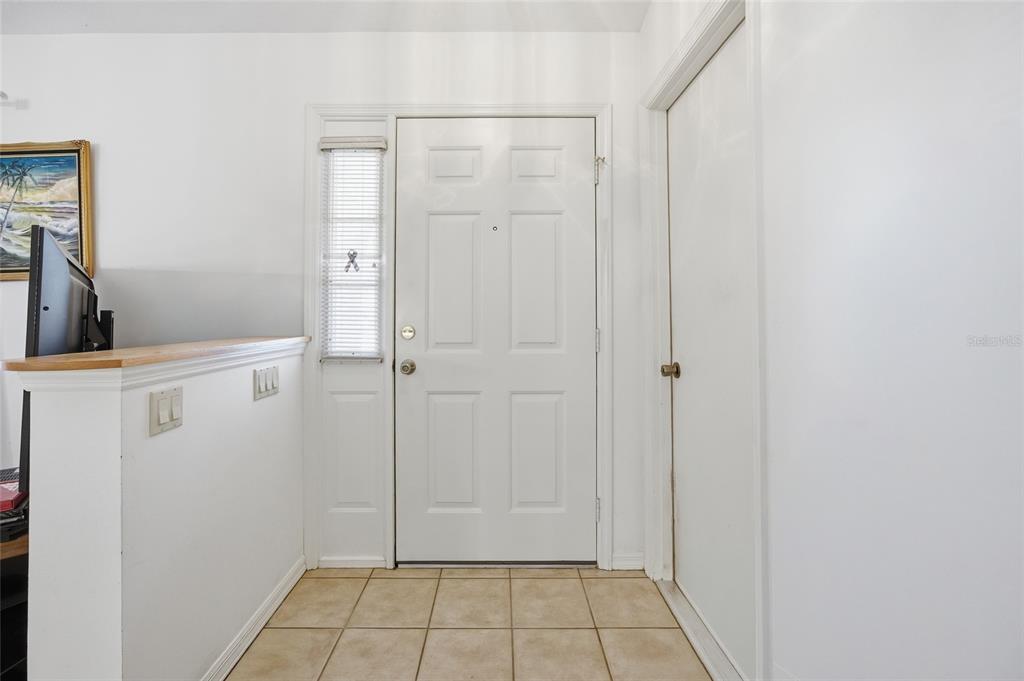 An entryway features a white front door, a side window, and beige floor tiles — 712 MAGNOLIA AVENUE, INVERNESS, FL
