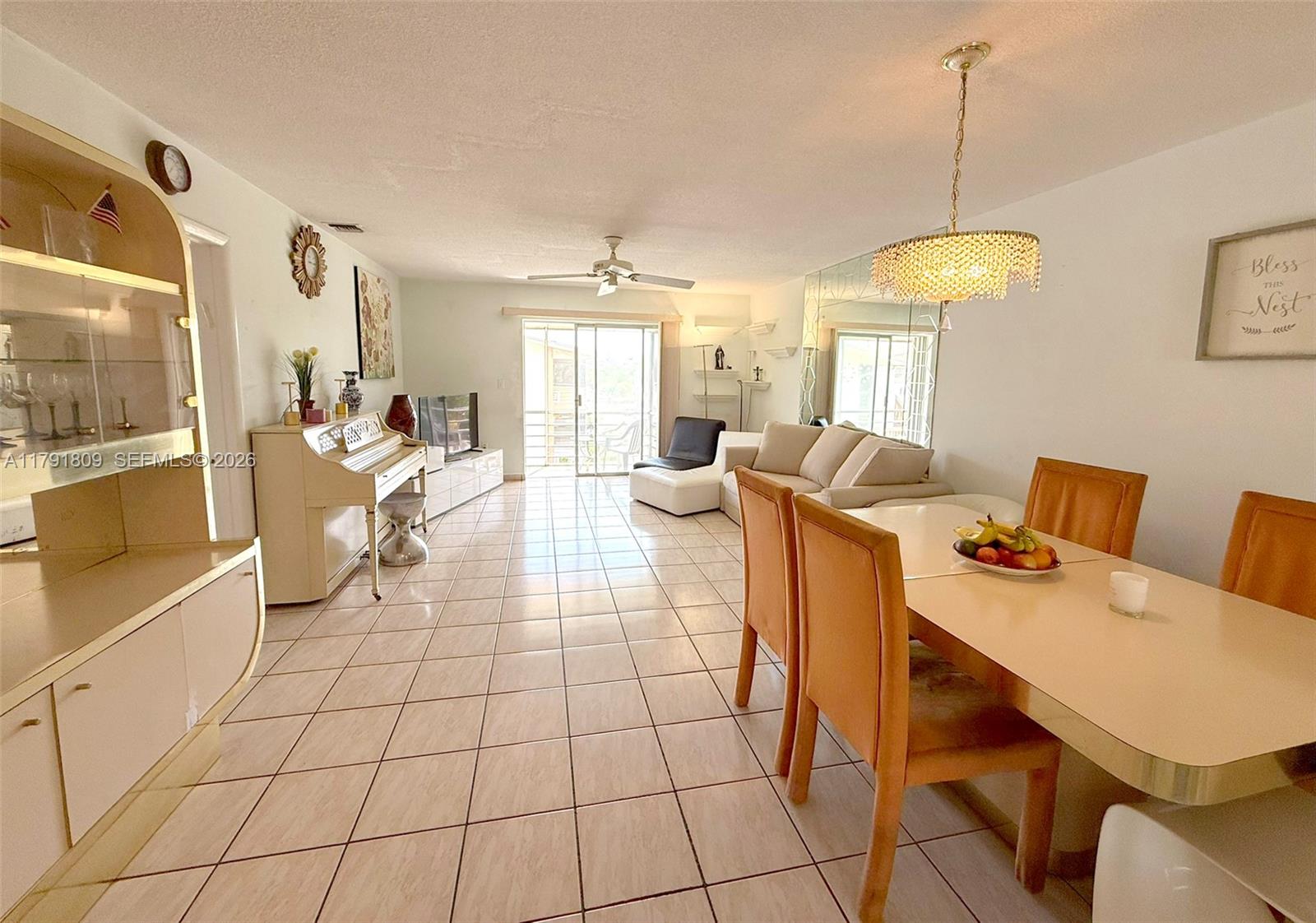 A living and dining area features tile floors, a crystal chandelier, and a white piano — 1355 NE 167th St # 302, Miami FL 33162, MIAMI, FL