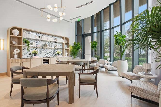 A modern lounge features a wooden table, chairs, built-in shelving, and floor-to-ceiling windows — 3015 S YSABELLA AVENUE UNIT 601, TAMPA, FL