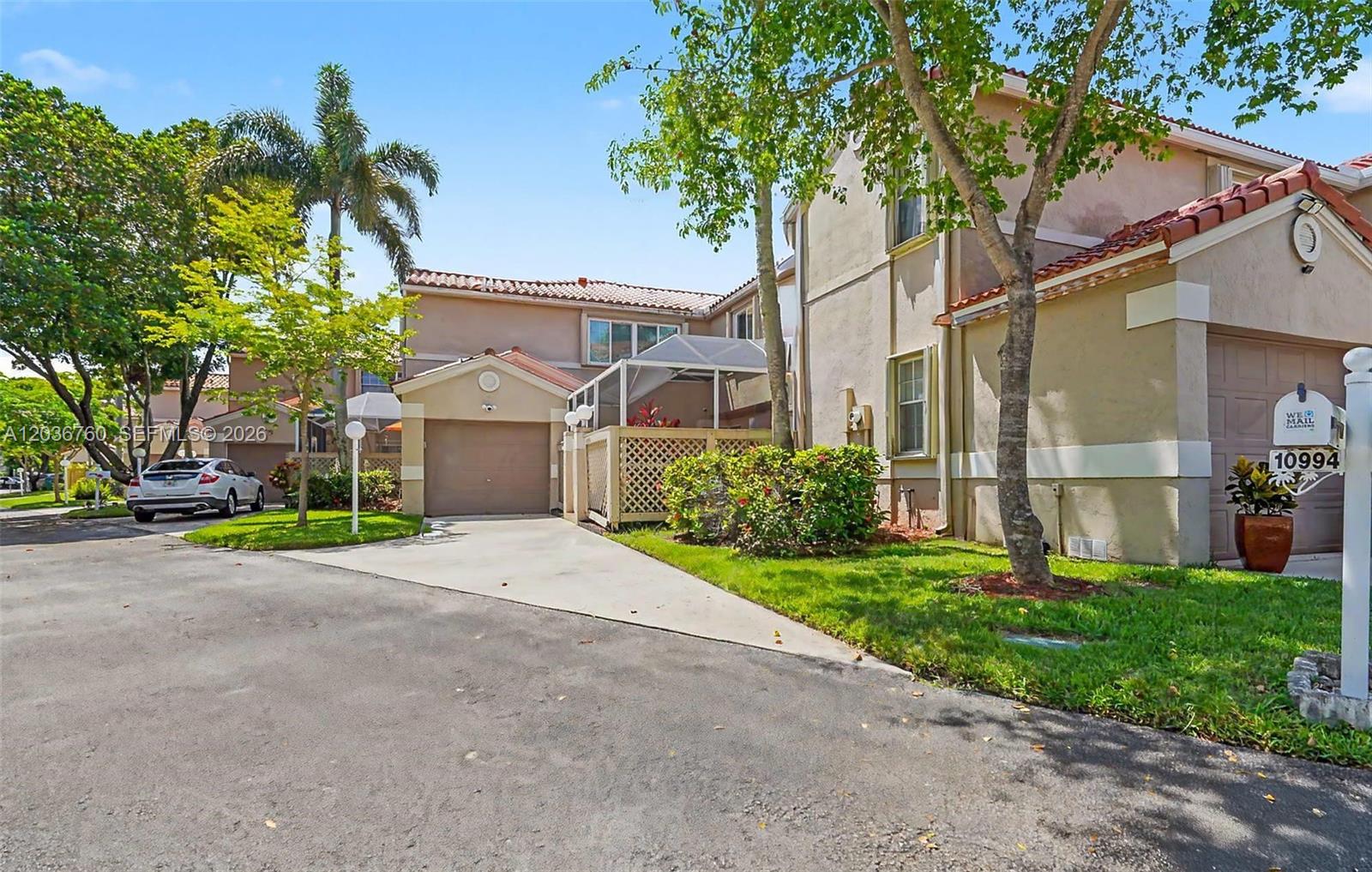 A two-story townhouse with a garage, a screened-in patio, and a driveway — 10994 Neptune Dr, Cooper City FL 33026, COOPER CITY, FL