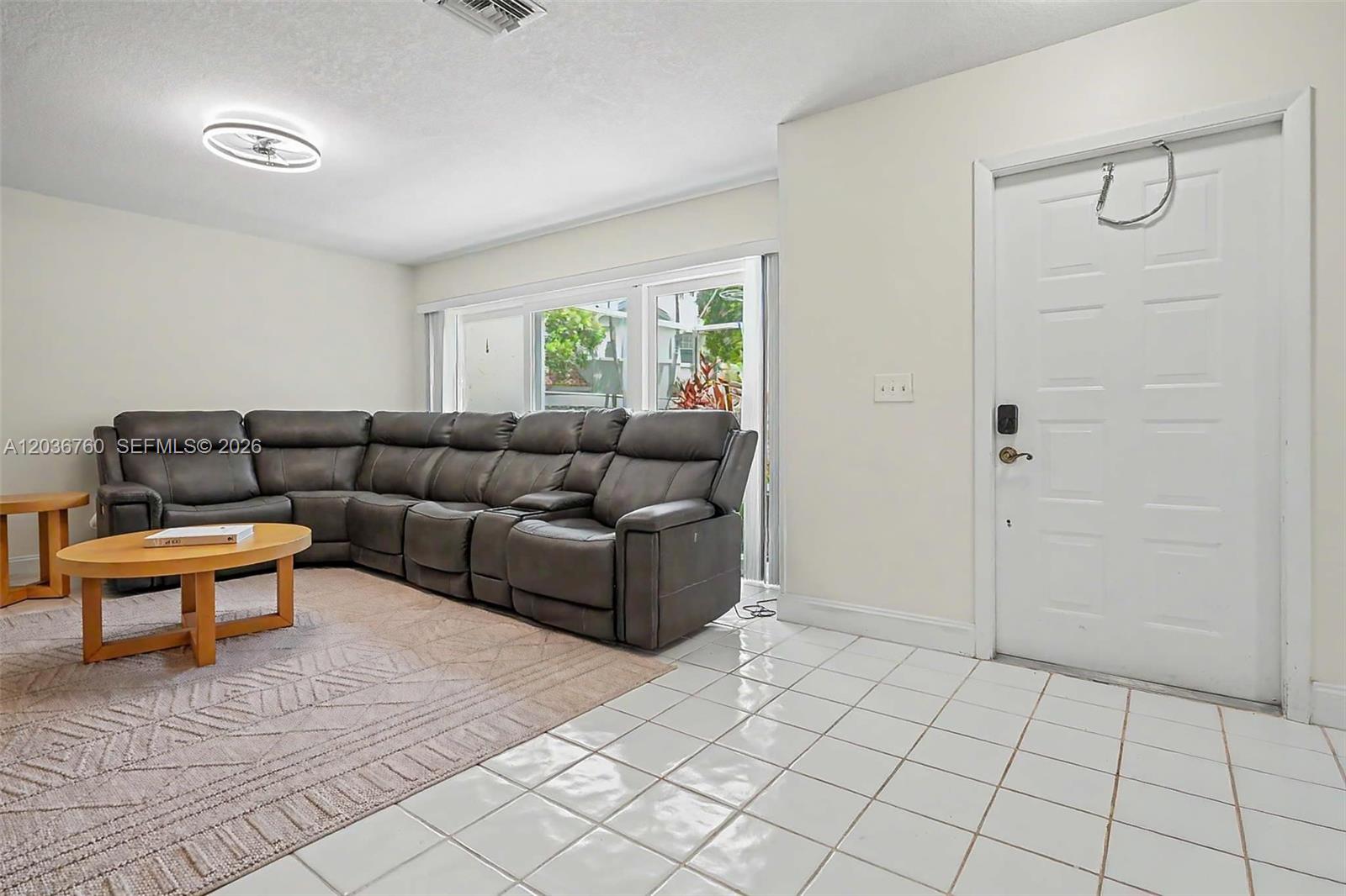 A living room features a gray sectional sofa, a coffee table, and white tile flooring — 10994 Neptune Dr, Cooper City FL 33026, COOPER CITY, FL