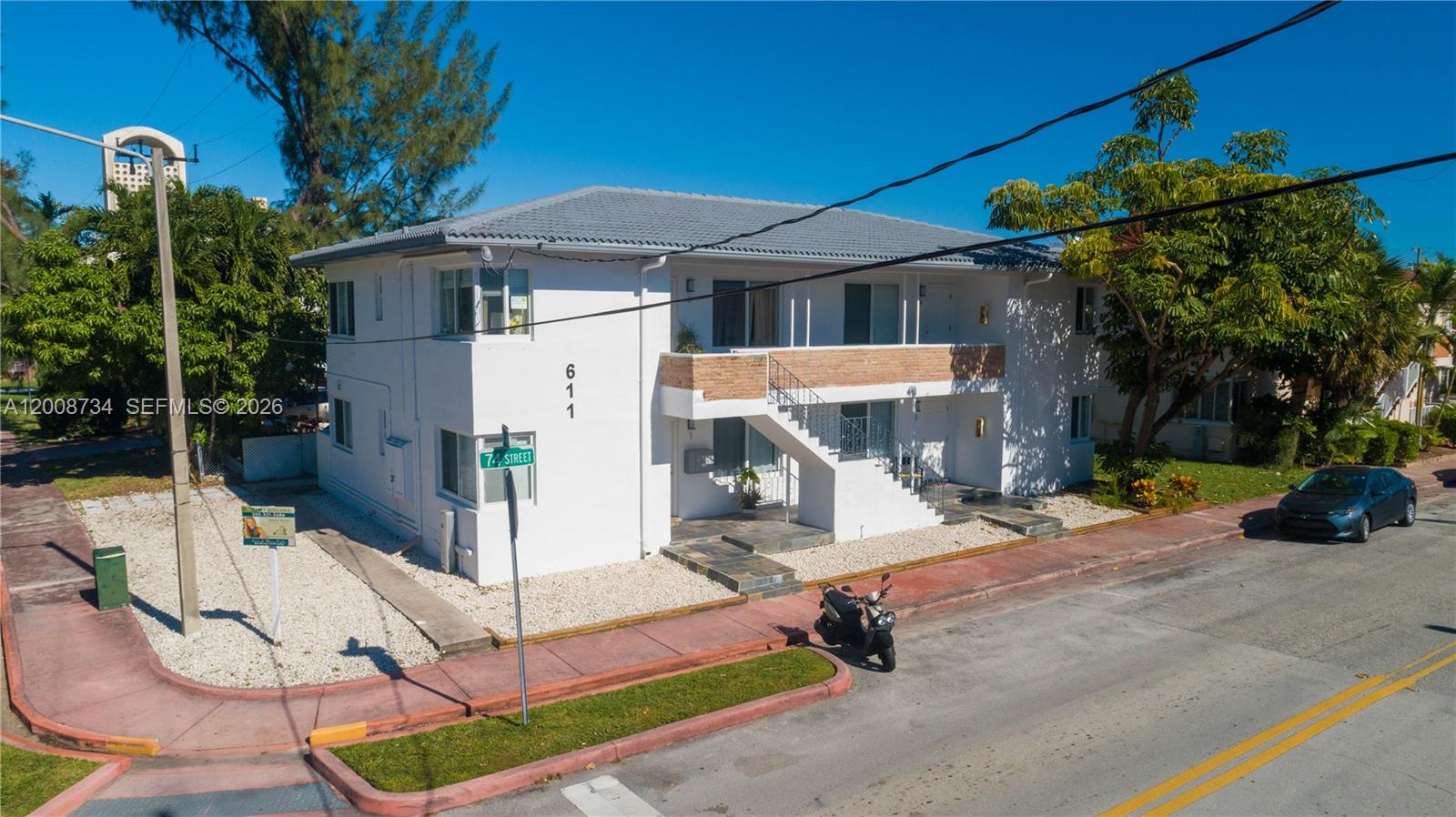 A two-story white apartment building with an exterior staircase stands on a corner lot — 611 74th St, Miami Beach FL 33141, MIAMI BEACH, FL