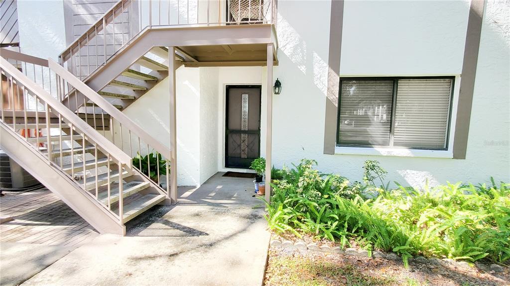 An exterior view of a building entrance with a staircase and a large window — 603 BALDWIN AVENUE UNIT B, SAFETY HARBOR, FL