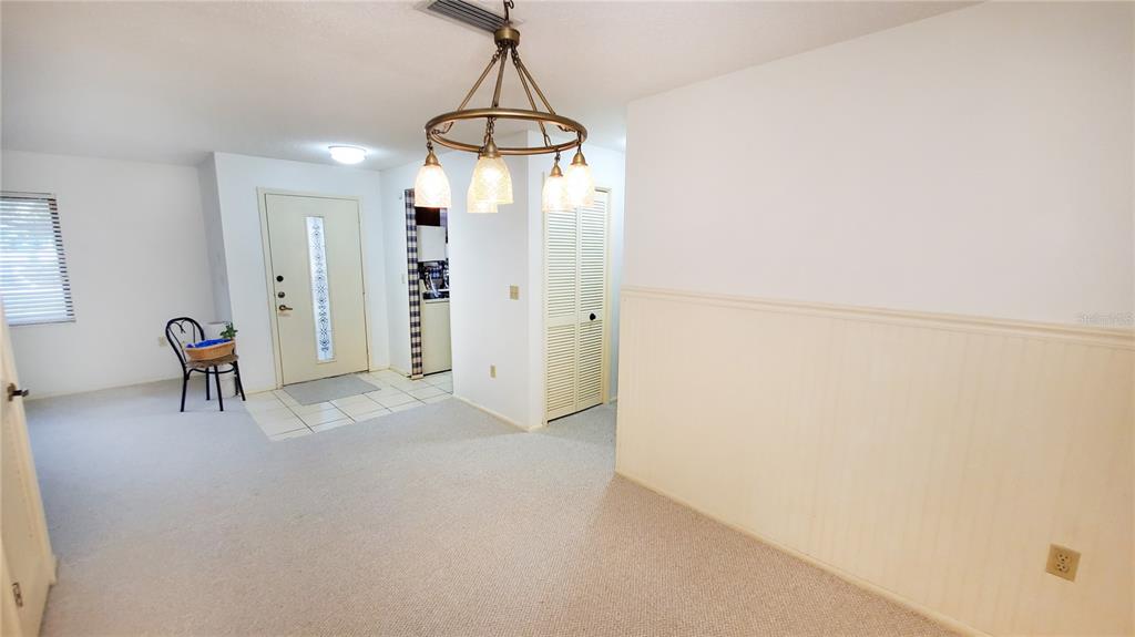 A dining area features a chandelier, beige carpeting, and a white front door — 603 BALDWIN AVENUE UNIT B, SAFETY HARBOR, FL