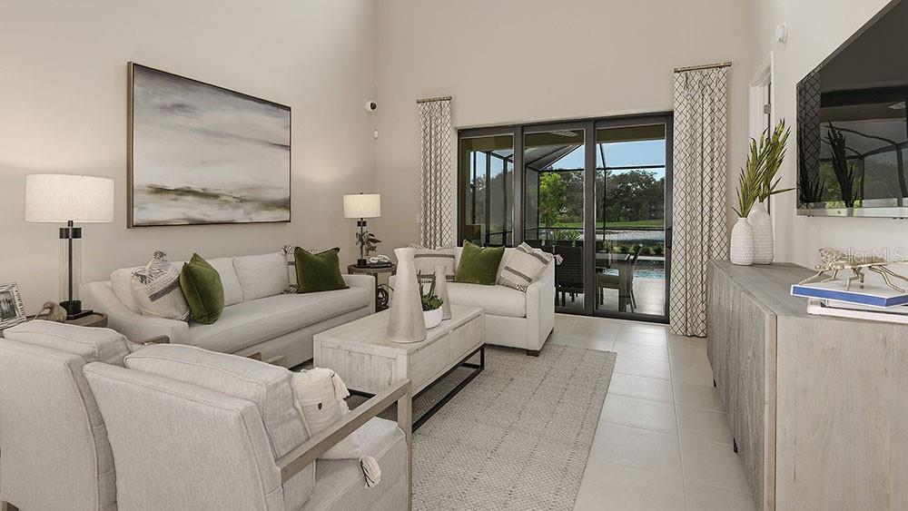 A bright living room features light-colored sofas, a coffee table, and sliding glass patio doors — 763 STEEL DRIVE, APOLLO BEACH, FL