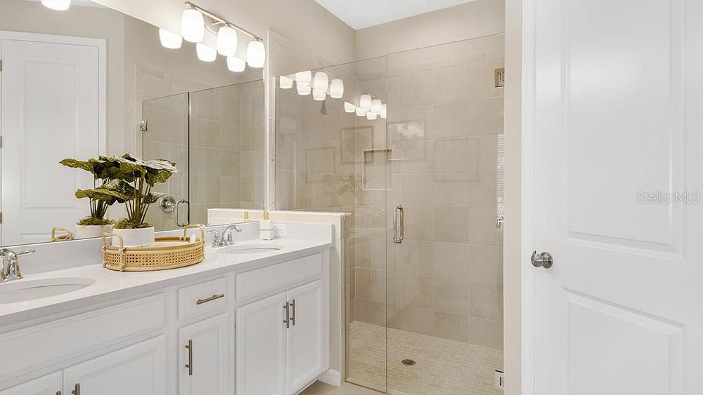 A bathroom features a white double vanity, a glass-enclosed shower, and neutral tile walls — 763 STEEL DRIVE, APOLLO BEACH, FL