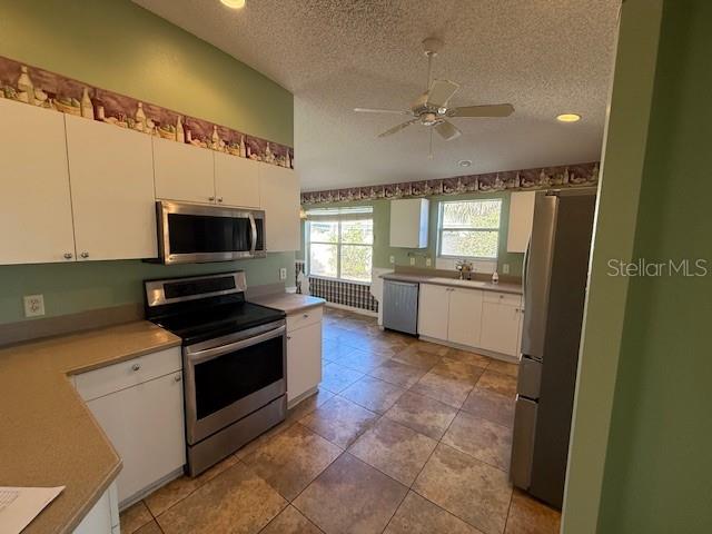 A kitchen features white cabinetry, stainless steel appliances, and light brown tile flooring — 17760 SE 91ST FREEDOM COURT, THE VILLAGES, FL