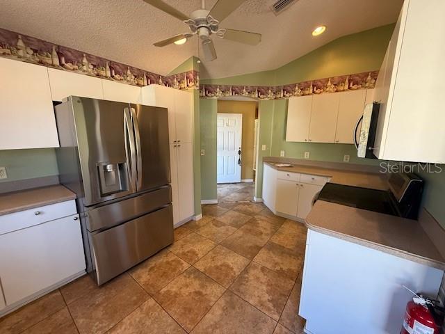 A kitchen features stainless steel appliances, white cabinetry, and light-colored tile flooring — 17760 SE 91ST FREEDOM COURT, THE VILLAGES, FL
