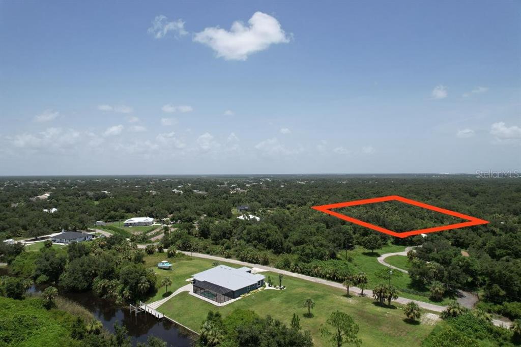 An aerial view shows a wooded lot outlined in red near a waterfront house — 1232 HARBOUR SUNSET COURT, PUNTA GORDA, FL