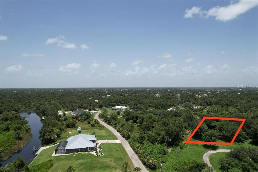 An aerial view shows a wooded lot outlined in red next to a residential house — 1232 HARBOUR SUNSET COURT, PUNTA GORDA, FL