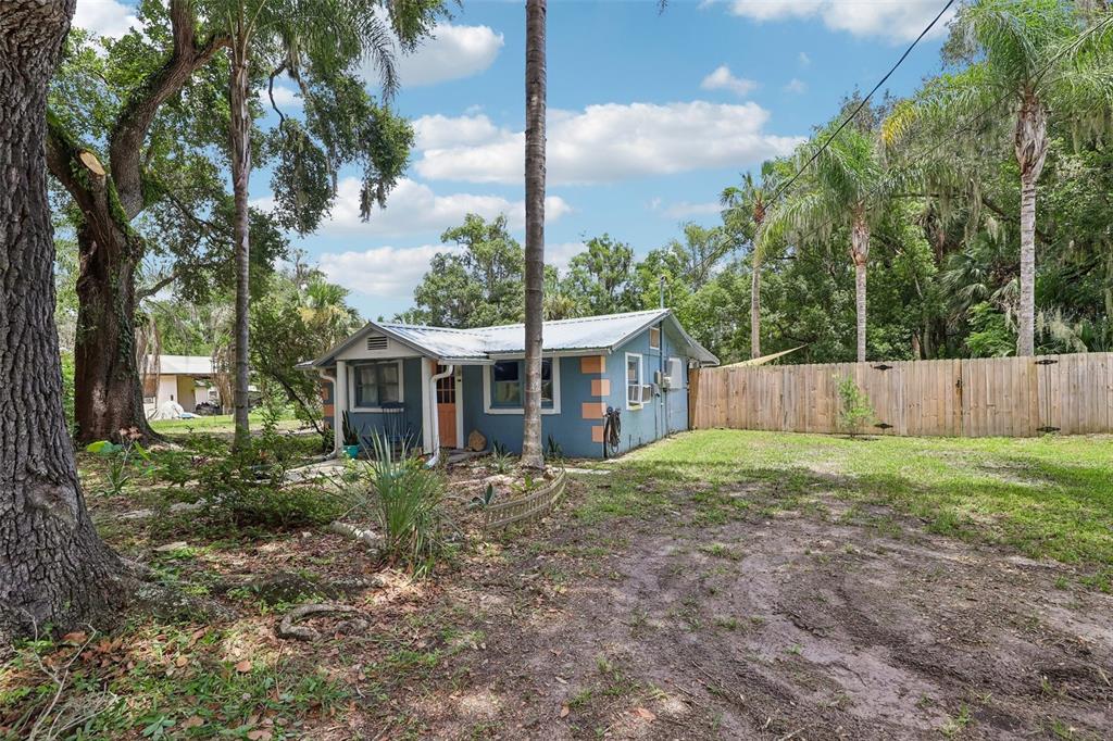 A small blue house with a metal roof sits in a grassy, tree-filled yard — 521 S 9TH STREET, CRESCENT CITY, FL