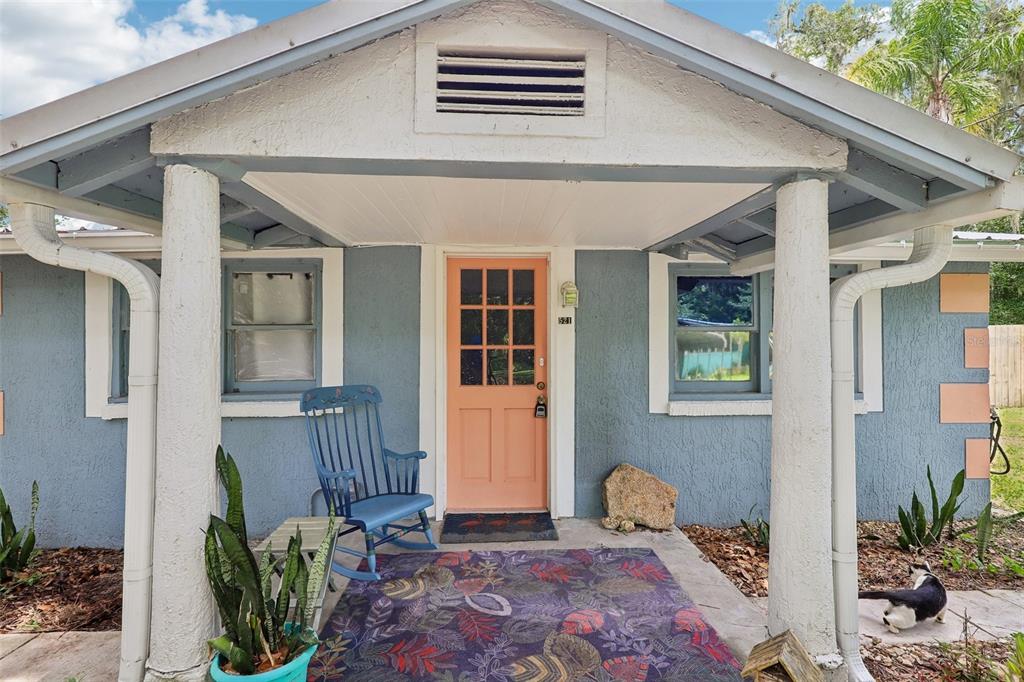 A blue house exterior features a peach-colored front door, a porch, and a rocking chair — 521 S 9TH STREET, CRESCENT CITY, FL