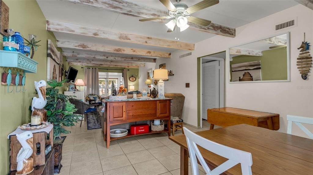 A living and dining area features exposed ceiling beams, tile flooring, and coastal decor — 5109 CLUB CIRCLE, LAKE WALES, FL