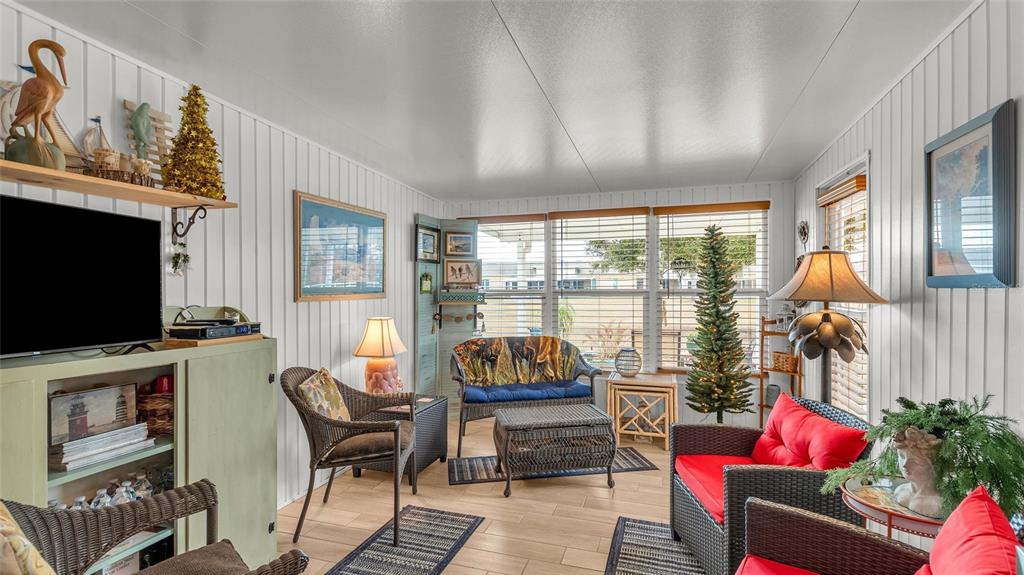 A sunroom features white paneled walls, wicker furniture, a television, and large windows — 5109 CLUB CIRCLE, LAKE WALES, FL