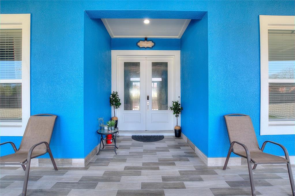 A bright blue exterior entryway features double glass doors, two chairs, and tiled flooring — 803 N 24TH STREET, HAINES CITY, FL