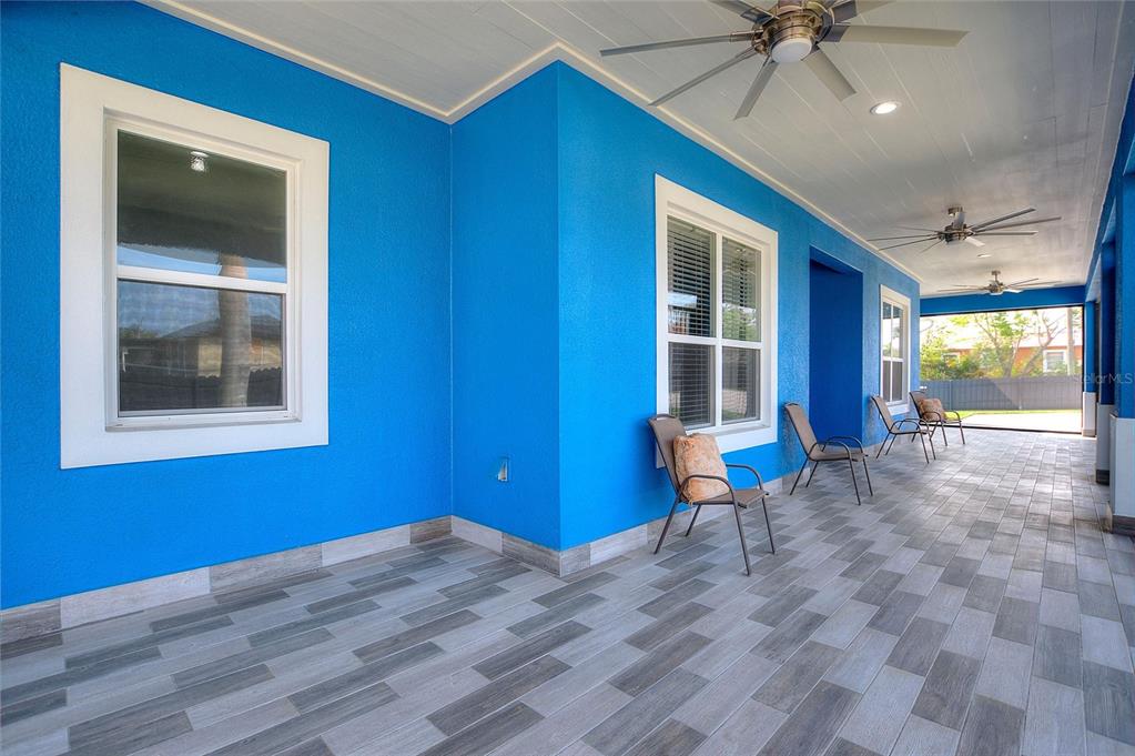 A covered outdoor patio features bright blue walls, tiled flooring, and multiple ceiling fans — 803 N 24TH STREET, HAINES CITY, FL