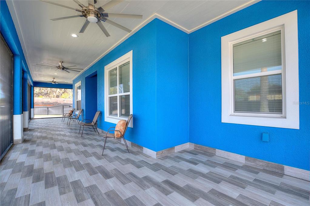 A covered patio features bright blue walls, wood-look tile flooring, and three ceiling fans — 803 N 24TH STREET, HAINES CITY, FL
