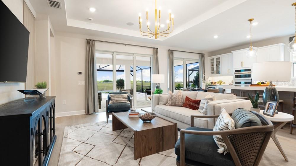 A living room with a sofa, armchairs, coffee table, and an open kitchen in the background — 14236 DUNLIN AVENUE, PUNTA GORDA, FL