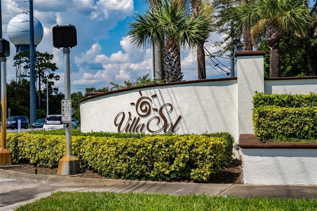 A white stucco wall features the Villa Sol sign and landscaping near a road — 3012 VILLA PRECIOSA DRIVE, KISSIMMEE, FL
