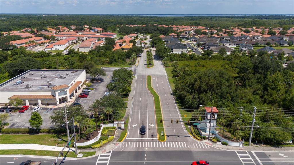 An aerial view shows a commercial building, a gated community entrance, and surrounding residential neighborhoods — 3012 VILLA PRECIOSA DRIVE, KISSIMMEE, FL