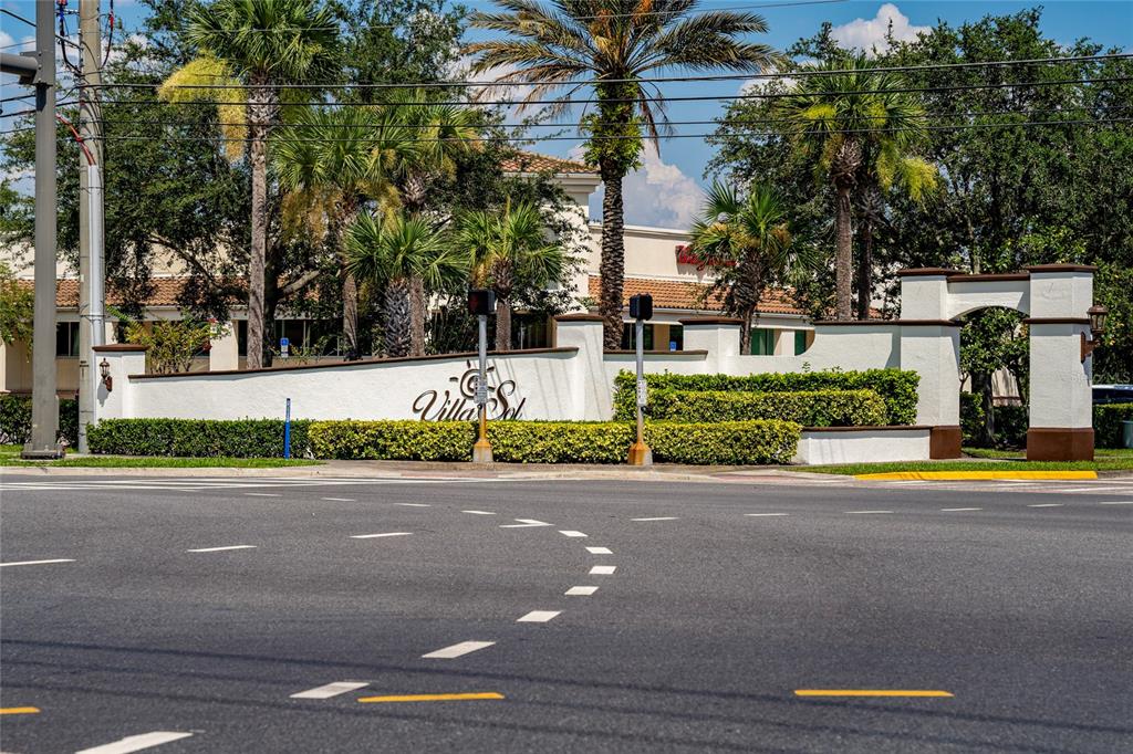 A white stucco entrance wall with the Villa Sol sign stands behind a paved intersection — 3012 VILLA PRECIOSA DRIVE, KISSIMMEE, FL