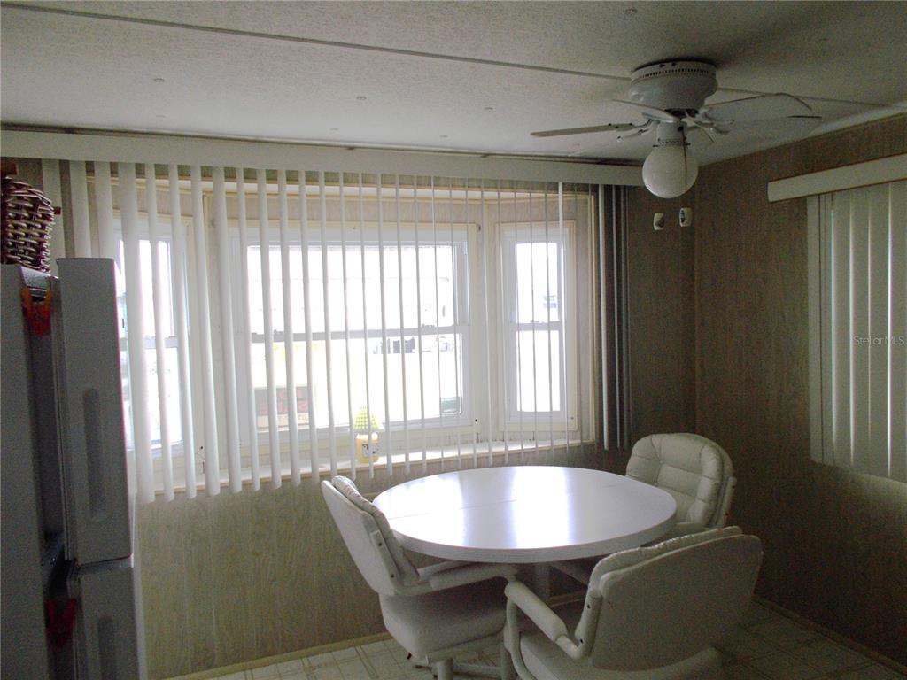 A dining area features a round table, white chairs, vertical blinds, and a ceiling fan — 6427 FLEETWOOD COURT, NORTH PORT, FL
