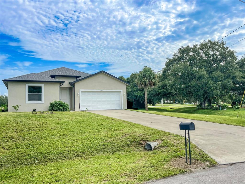 A single-story house with a beige exterior, a two-car garage, and a large front lawn — 2013 ODESSA CIRCLE, LABELLE, FL