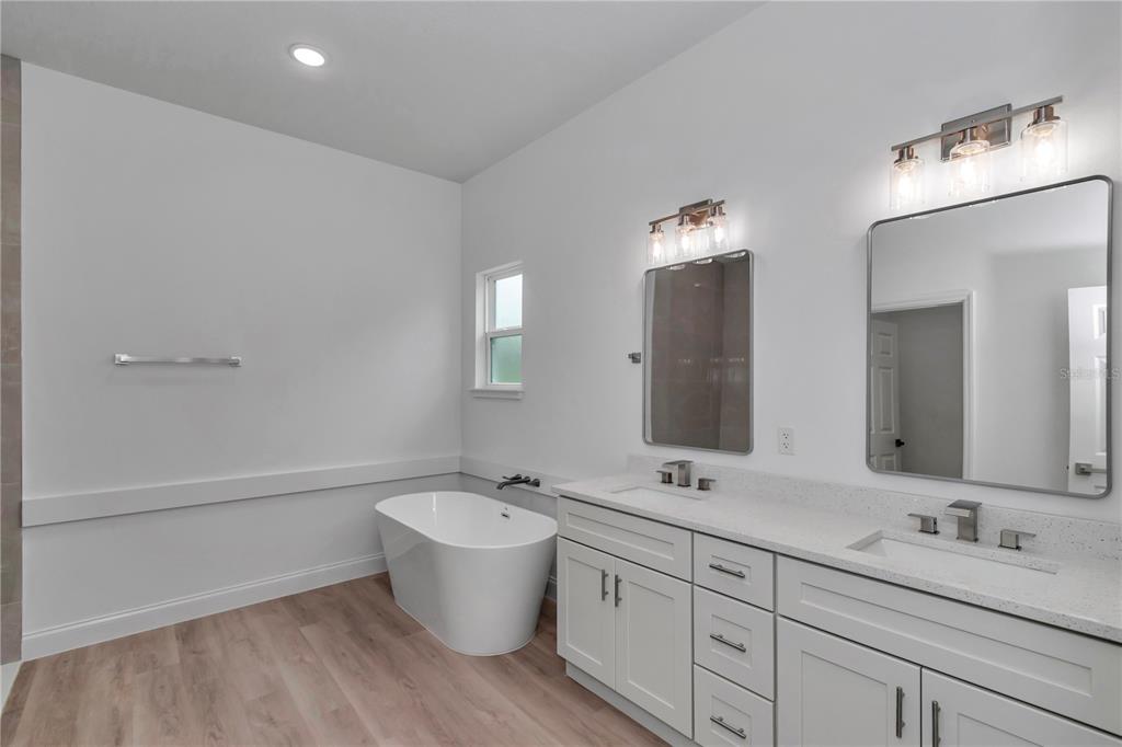 A white stucco house exterior features a two-car garage, stone accents, and a paver driveway — 8737 N RAIDIN DRIVE, CITRUS SPRINGS, FL