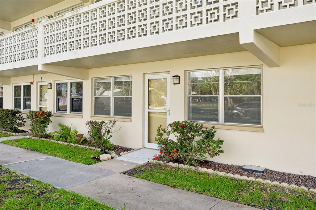 A ground-level apartment entrance features a white door, large windows, and a concrete walkway — 8101 11TH STREET N UNIT 125, ST PETERSBURG, FL