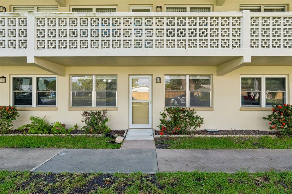 The exterior of a two-story building features a white concrete balcony railing and ground-level windows — 8101 11TH STREET N UNIT 125, ST PETERSBURG, FL