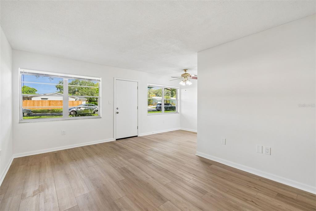 A bright living room with white walls, light wood-look flooring, and two windows — 8101 11TH STREET N UNIT 125, ST PETERSBURG, FL