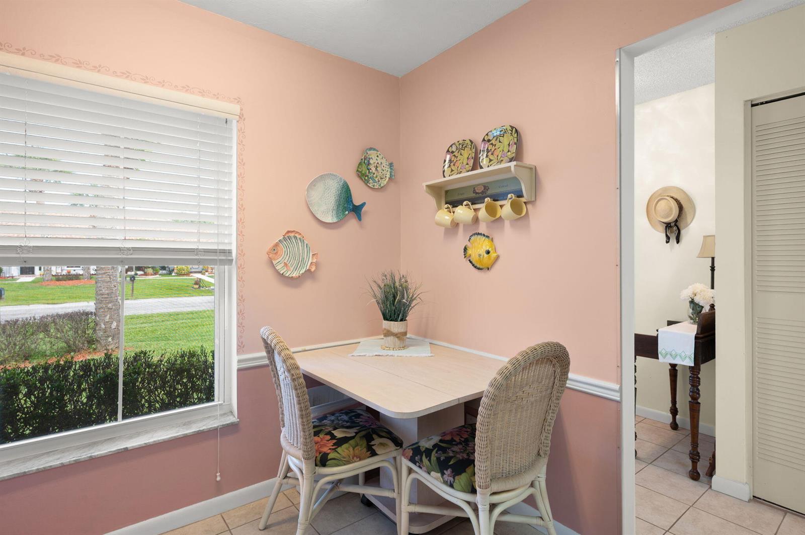 A breakfast nook features a small table, two wicker chairs, and fish-themed wall decor — 945 Savannas Point Drive # B, Fort Pierce FL 34982, FORT PIERCE, FL
