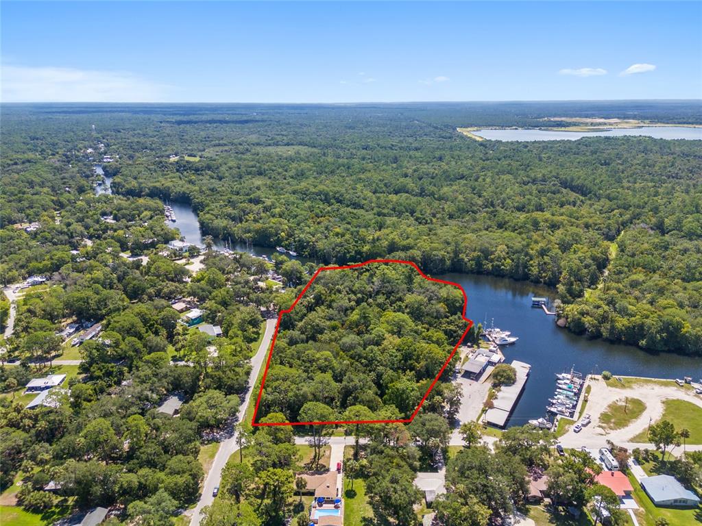 An aerial view shows a wooded lot outlined in red next to a boat marina — 0 HICKORY AVENUE, YANKEETOWN, FL