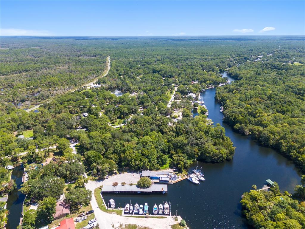 An aerial view shows a marina with docked boats along a river surrounded by forest — 0 HICKORY AVENUE, YANKEETOWN, FL