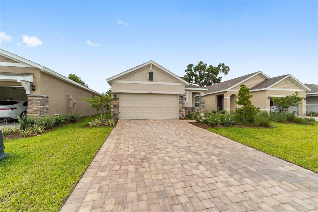 A single-story house with a beige exterior, stone accents, and a paved driveway — 4111 NW 44TH CIRCLE, OCALA, FL