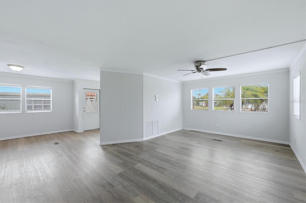 An empty living room with light wood-look flooring, white walls, and a ceiling fan — 3310 BLUE JAY LANE, ENGLEWOOD, FL