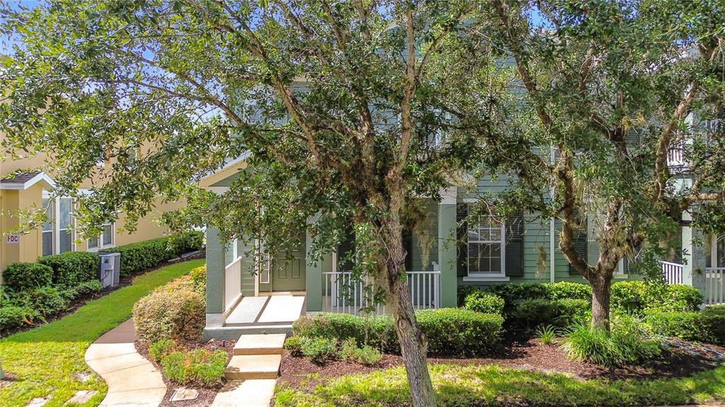 A two-story green house with a front porch and a large tree in the yard — 10338 LAKE DISTRICT LANE UNIT S, ORLANDO, FL