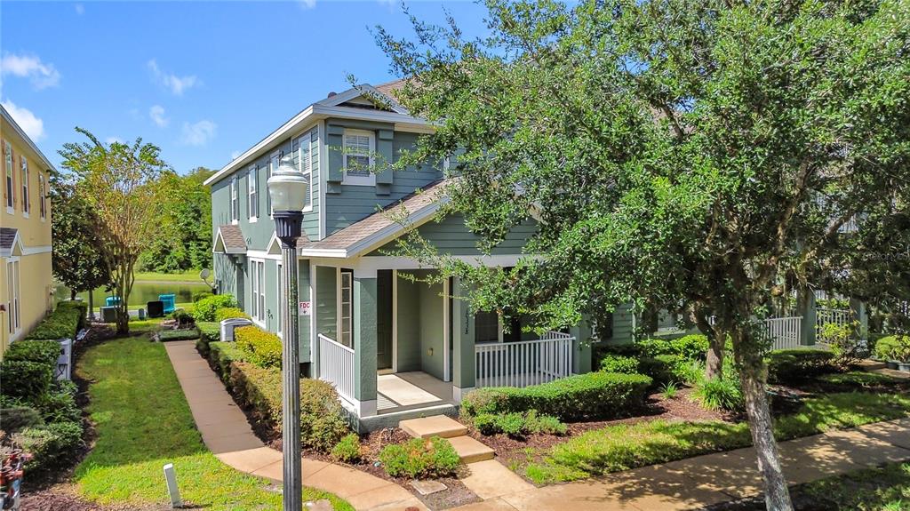 A two-story green house with a covered front porch and a sidewalk leading to it — 10338 LAKE DISTRICT LANE UNIT S, ORLANDO, FL