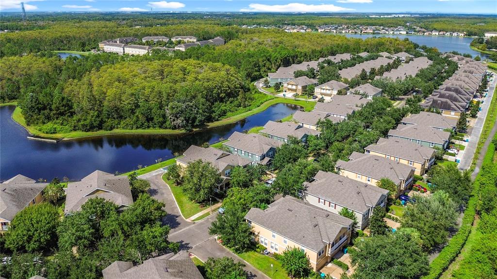 An aerial view shows a residential neighborhood with multi-story houses, trees, and a winding pond — 10338 LAKE DISTRICT LANE UNIT S, ORLANDO, FL