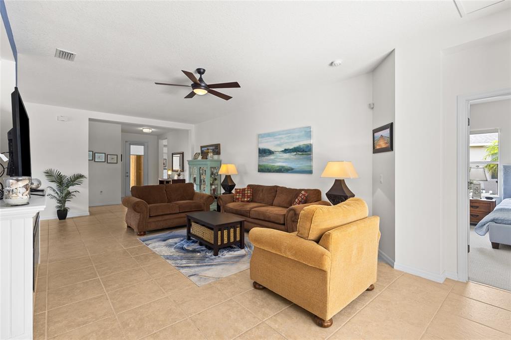 A living room features tile flooring, brown sofas, a yellow armchair, and a ceiling fan — 11739 FENNEMORE WAY, PARRISH, FL