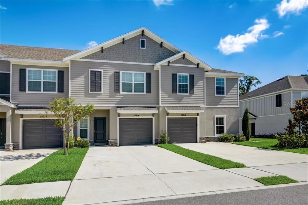 A two-story townhouse exterior features gray siding, a shingled roof, and two attached garages — 10916 QUICKWATER COURT, RIVERVIEW, FL