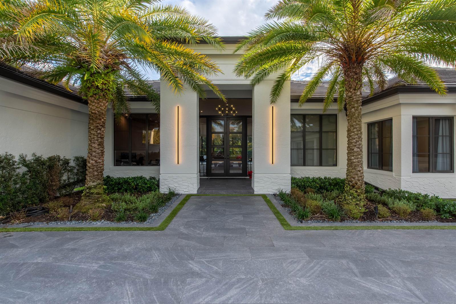 A modern white house exterior features a stone walkway, two palm trees, and glass doors — 1768 Breakers West Boulevard W, West Palm Beach FL 33411, WEST PALM BEACH, FL