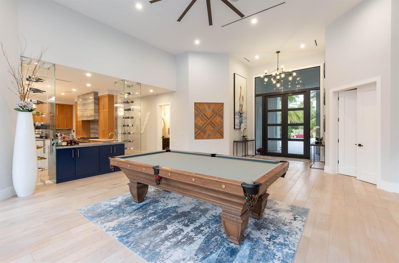 A game room features a pool table, a glass-enclosed wine display, and a modern chandelier — 1768 Breakers West Boulevard W, West Palm Beach FL 33411, WEST PALM BEACH, FL