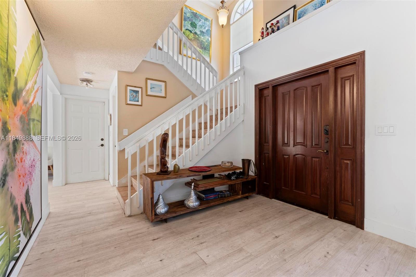 An entryway features a wooden front door, a staircase with white railings, and wood-look flooring — 4471 SW 154th Ct, Miami FL 33185, MIAMI, FL