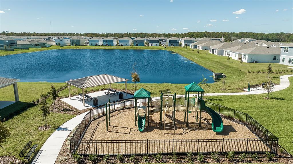 An aerial view shows a fenced playground and a covered pavilion beside a large pond — 5431 ISLA SAONA DRIVE, KISSIMMEE, FL