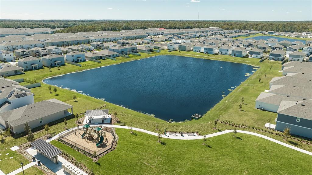 An aerial view shows a suburban neighborhood with a central pond, playground, and park area — 5431 ISLA SAONA DRIVE, KISSIMMEE, FL