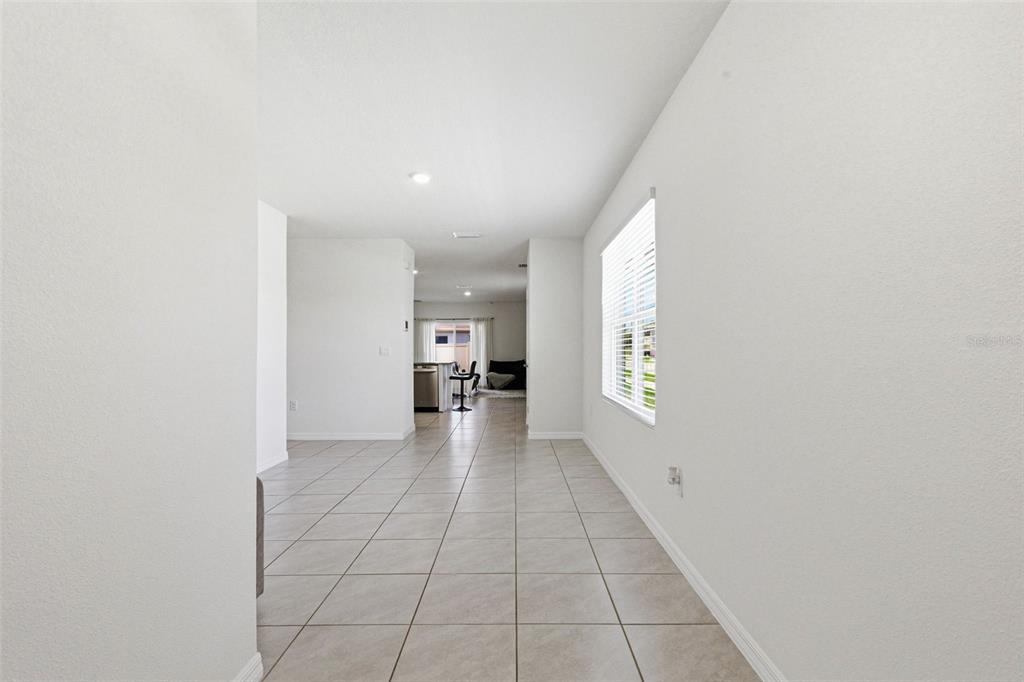 A tiled dining area leads into an open kitchen with a view of the neighborhood — 2959 COMMON FIG RUN, WESLEY CHAPEL, FL