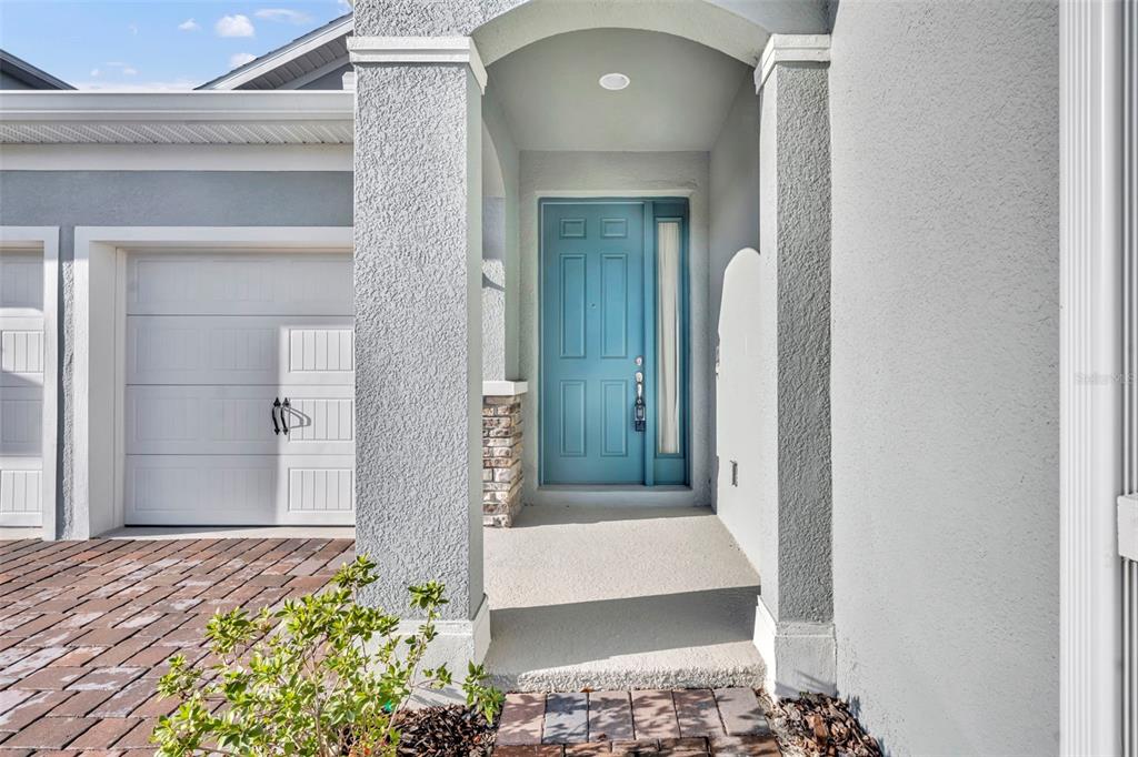 A teal front door sits under a covered entryway next to a white garage door — 19268 ALLIUM PLACE, ORLANDO, FL